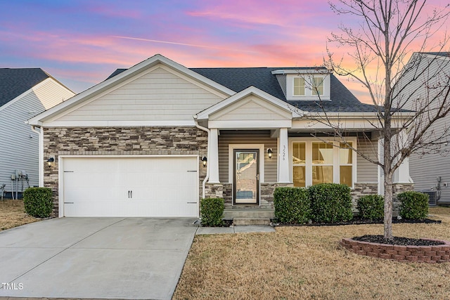 craftsman-style house with a garage, stone siding, roof with shingles, and driveway