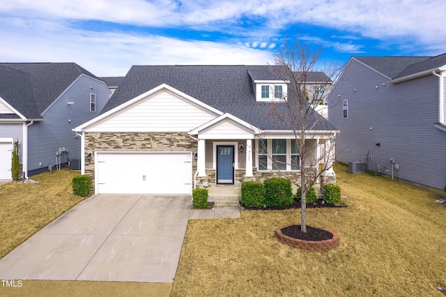 view of front of home featuring concrete driveway, a front yard, central AC unit, stone siding, and an attached garage