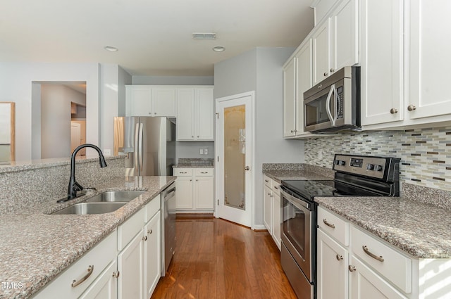 kitchen with visible vents, backsplash, dark wood-style floors, stainless steel appliances, and a sink