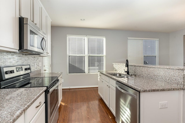 kitchen with backsplash, dark wood-type flooring, white cabinets, stainless steel appliances, and a sink