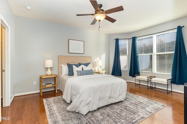 bedroom featuring baseboards, wood finished floors, and a ceiling fan