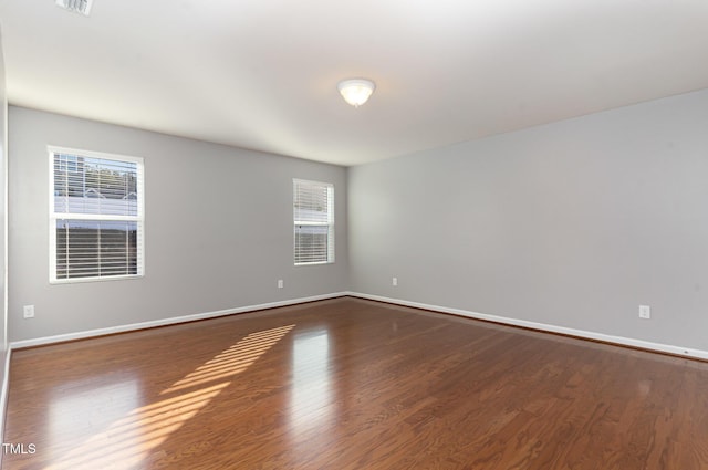 spare room featuring baseboards and dark wood-style flooring