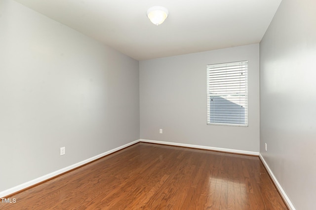 unfurnished room with dark wood-type flooring and baseboards