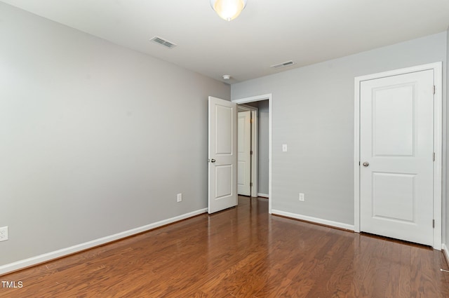 unfurnished bedroom featuring wood finished floors, visible vents, and baseboards