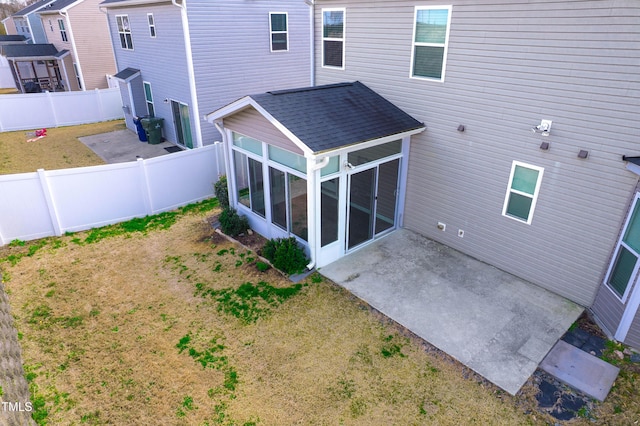 back of house with a sunroom, roof with shingles, a fenced backyard, a yard, and a patio