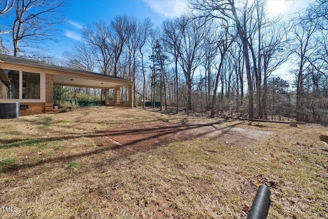 view of yard featuring a carport, cooling unit, and driveway