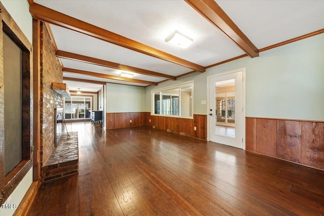 spare room featuring a wainscoted wall, beamed ceiling, wood-type flooring, wood walls, and a fireplace