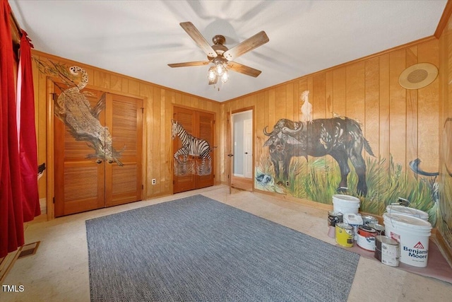 interior space with visible vents, wood walls, crown molding, and ceiling fan