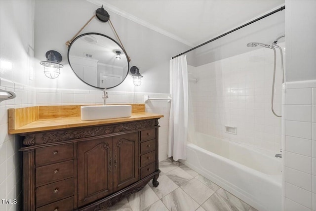 bathroom featuring vanity, shower / bathtub combination with curtain, a wainscoted wall, ornamental molding, and tile walls