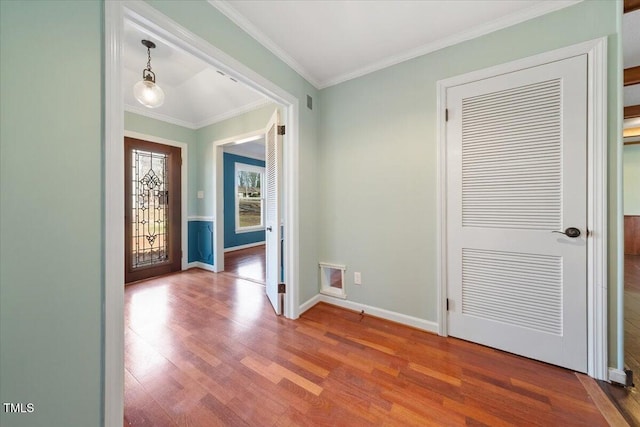 entrance foyer with crown molding, wood finished floors, baseboards, and visible vents