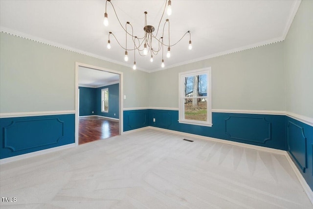 empty room with plenty of natural light, a notable chandelier, and wainscoting