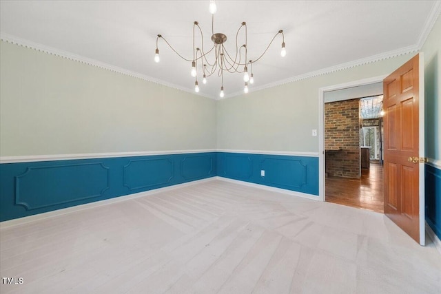 unfurnished room with a notable chandelier, a wainscoted wall, wood finished floors, and ornamental molding