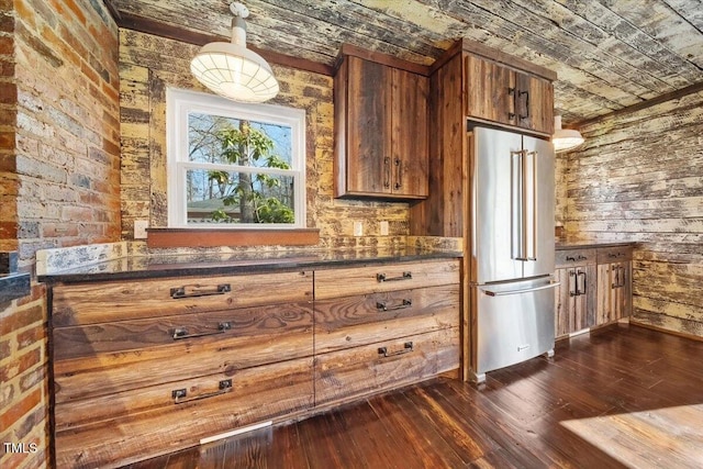 kitchen featuring dark countertops, high end fridge, dark wood finished floors, and brown cabinetry