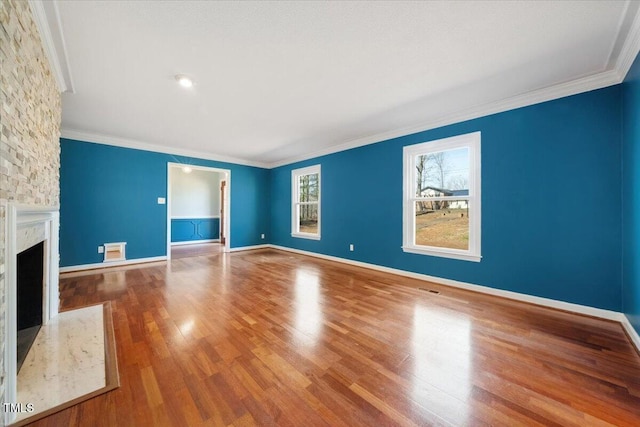 unfurnished living room with wood finished floors, baseboards, a high end fireplace, and ornamental molding