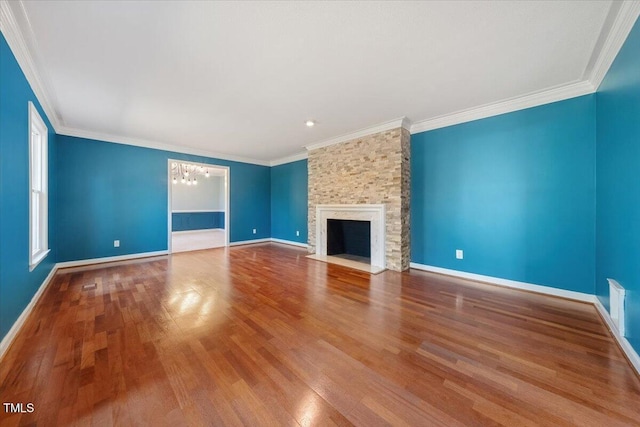 unfurnished living room featuring baseboards, a large fireplace, a notable chandelier, and wood finished floors