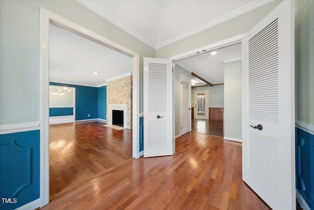 unfurnished living room featuring crown molding, baseboards, a fireplace, wood finished floors, and a notable chandelier