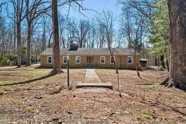 rear view of house featuring brick siding and a chimney