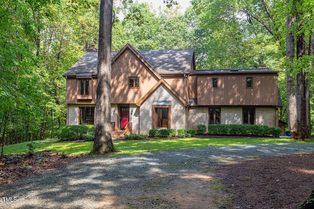 view of front facade with a front yard, brick siding, and a chimney