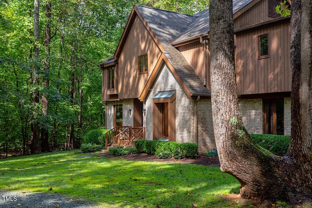 view of front of house featuring a front lawn, brick siding, and roof with shingles