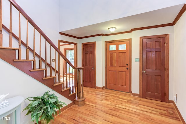 foyer entrance featuring stairs, crown molding, baseboards, and light wood-type flooring