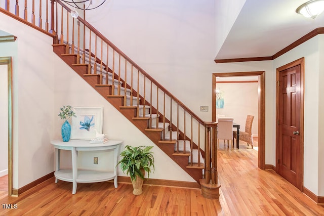 foyer entrance featuring stairway, baseboards, wood finished floors, and crown molding