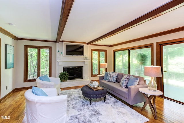 living room featuring baseboards, beam ceiling, light wood-style floors, and a glass covered fireplace