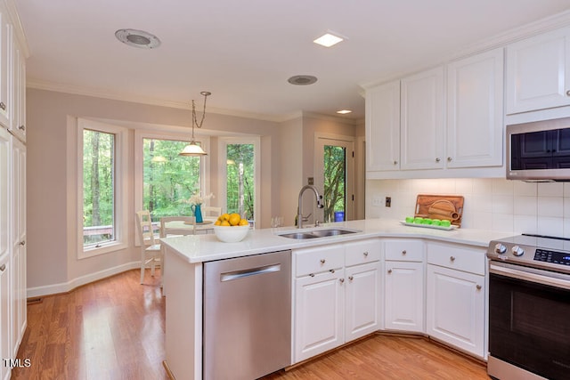 kitchen featuring a sink, a peninsula, crown molding, and stainless steel appliances