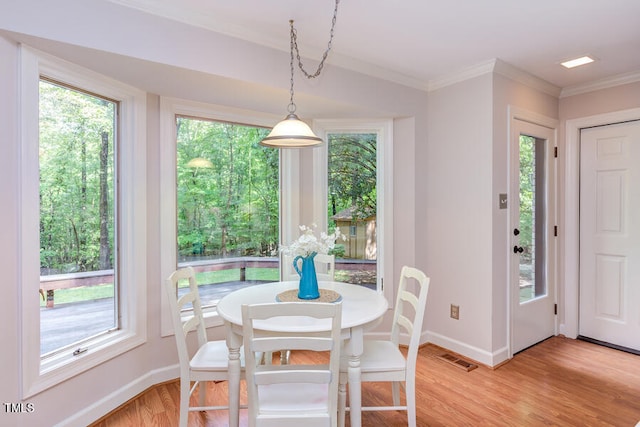 dining room featuring visible vents, baseboards, light wood-style flooring, and ornamental molding