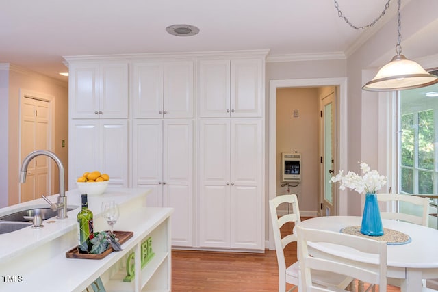 kitchen with heating unit, a sink, light countertops, white cabinetry, and light wood-type flooring