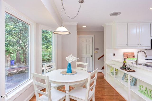 dining room featuring crown molding, baseboards, and light wood finished floors