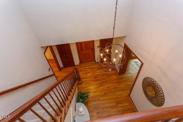 stairs featuring a notable chandelier and wood finished floors