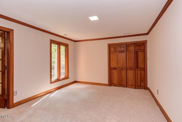 empty room with ornamental molding, baseboards, and light carpet