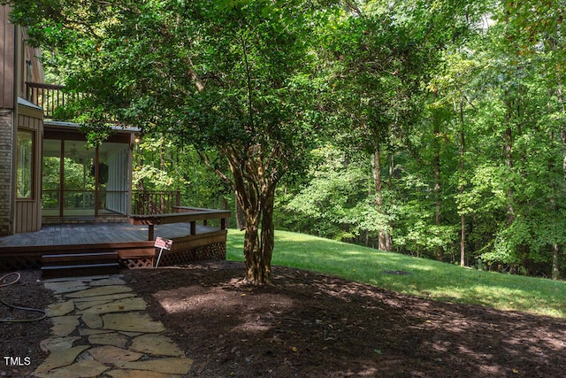 view of yard with a forest view, a sunroom, and a wooden deck