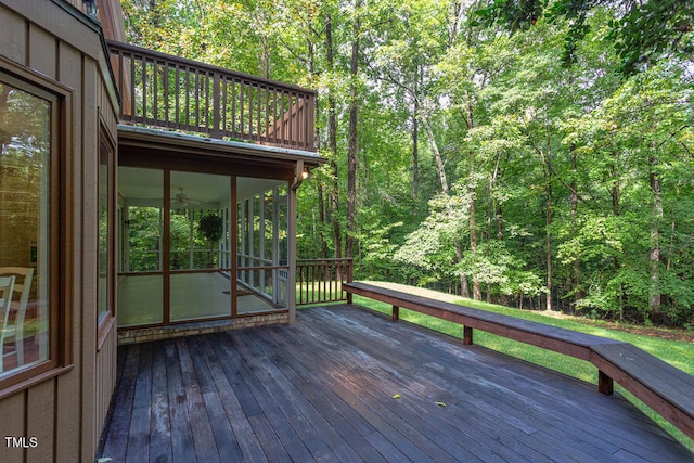 wooden terrace with a wooded view and a sunroom