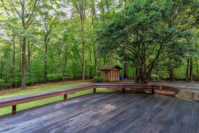 wooden deck with an outdoor structure, a wooded view, and a shed