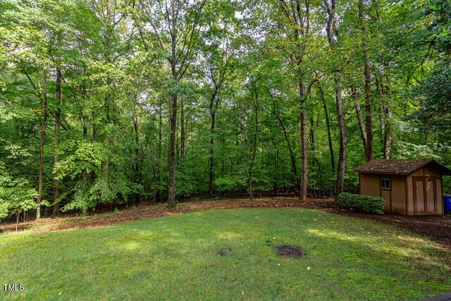 view of yard featuring an outbuilding, a storage unit, and a wooded view