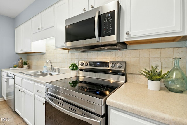 kitchen featuring a sink, backsplash, white cabinetry, appliances with stainless steel finishes, and light countertops