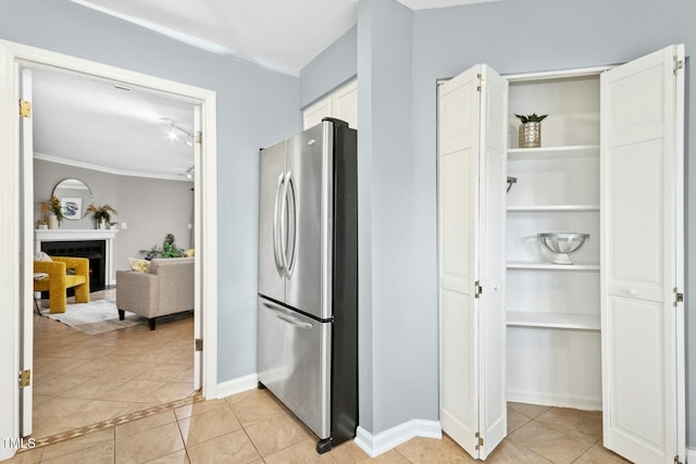 kitchen with baseboards, a fireplace, freestanding refrigerator, light tile patterned flooring, and white cabinetry