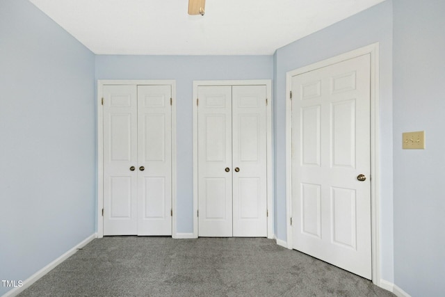 unfurnished bedroom featuring baseboards, carpet floors, two closets, and ceiling fan