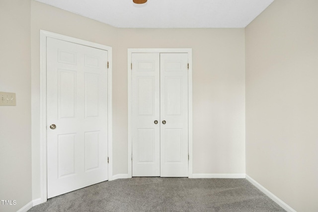 unfurnished bedroom with a closet, baseboards, and carpet