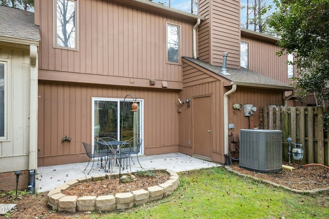 back of house featuring central AC unit, a shingled roof, a patio, and fence