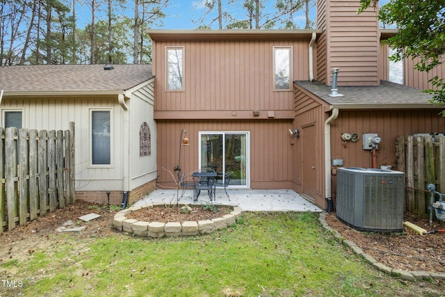 rear view of property with central air condition unit, a patio, a yard, and fence