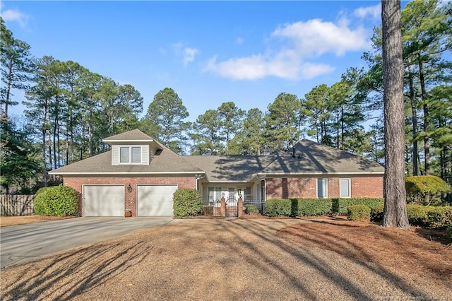 view of front of house with driveway, brick siding, an attached garage, and fence