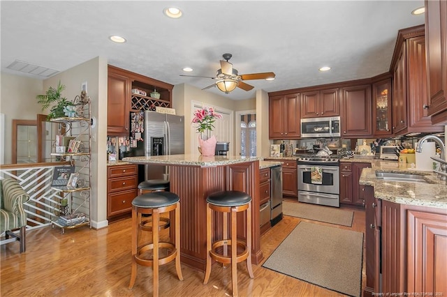 kitchen with a sink, stainless steel appliances, a breakfast bar, and light wood-style flooring