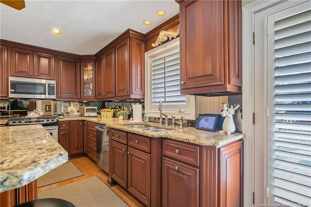 kitchen with light stone countertops, light wood finished floors, recessed lighting, a sink, and stainless steel appliances