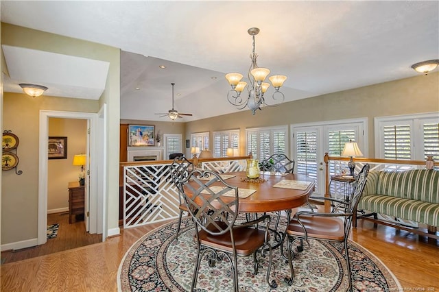 dining area featuring ceiling fan with notable chandelier, wood finished floors, recessed lighting, baseboards, and vaulted ceiling