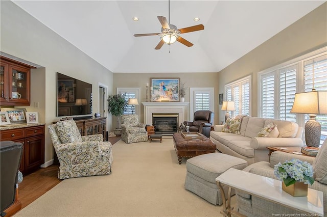 living area with ceiling fan, high vaulted ceiling, a glass covered fireplace, and recessed lighting