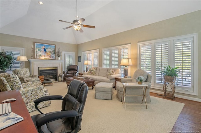 living area with a glass covered fireplace, high vaulted ceiling, ceiling fan, and wood finished floors