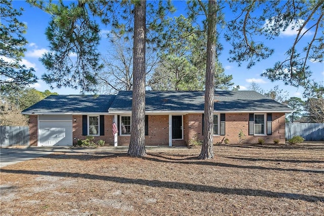 ranch-style house featuring brick siding, an attached garage, driveway, and fence