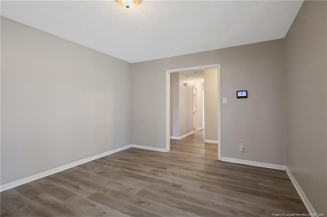 spare room featuring wood finished floors, baseboards, and a textured ceiling